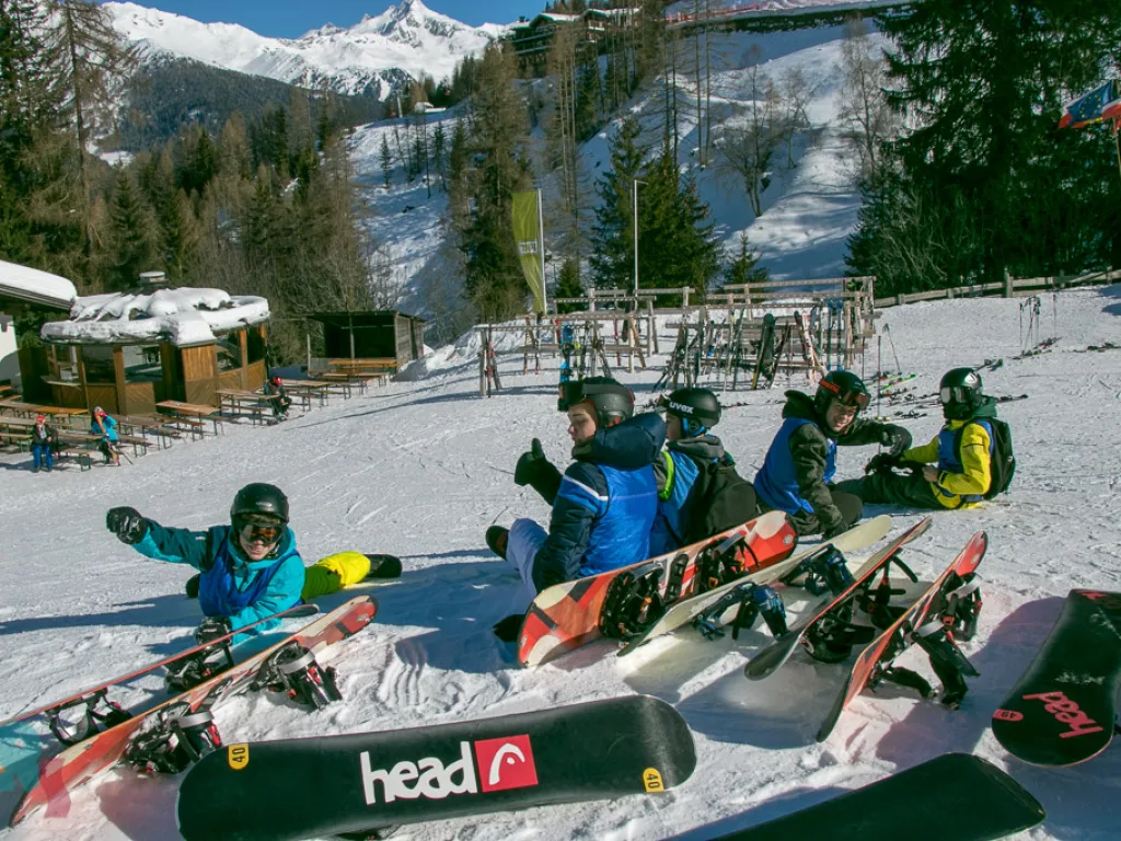 Jugendliche liegen mit Snowboards im Schnee.
